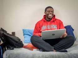 Student in dorm room using laptop