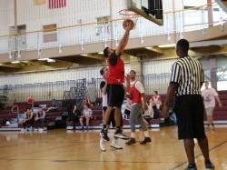 A referee standing on the left and 3 students playing basketball in the rec center gym